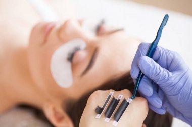 Kirpiklerini uzat. Sahte kirpikler. Kirpik uzatma prosedürü. Profesyonel stilist, kadın kirpiklerini uzatıyor. Usta ve bir müşteri güzellik salonunda.