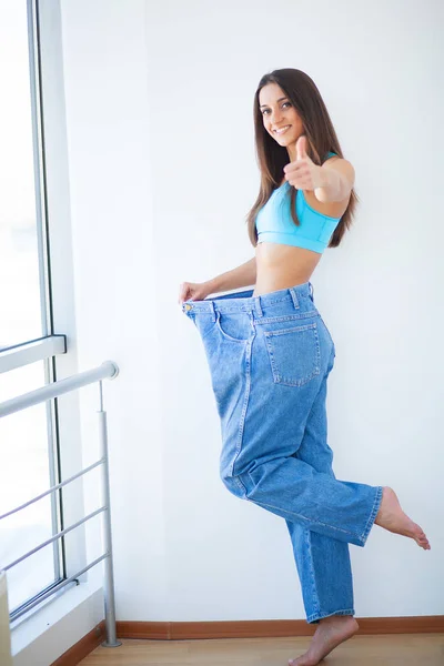 Dieet. Vrouw toont haar gewichtsverlies en het dragen van haar oude jeans — Stockfoto