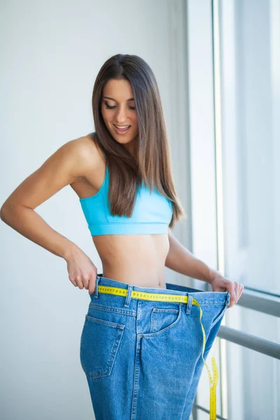 Dieta. Mujer muestra su pérdida de peso y el uso de sus vaqueros viejos —  Fotos de Stock