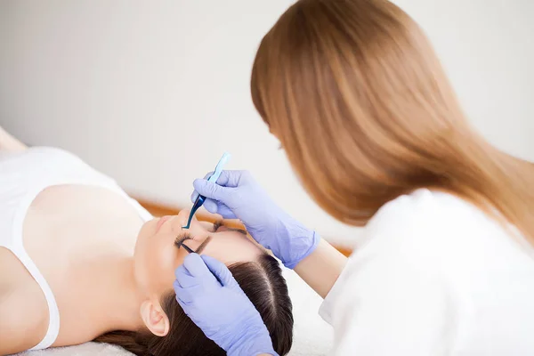 Extensiones de pestañas. Pestañas falsas. Procedimiento de extensión de pestañas. Estilista profesional que alarga las pestañas femeninas. Maestro y un cliente en un salón de belleza — Foto de Stock