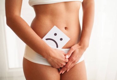 Kadın sağlığı. Kadın vücudu mide yakınındaki üzgün Smiley kartı tutan
