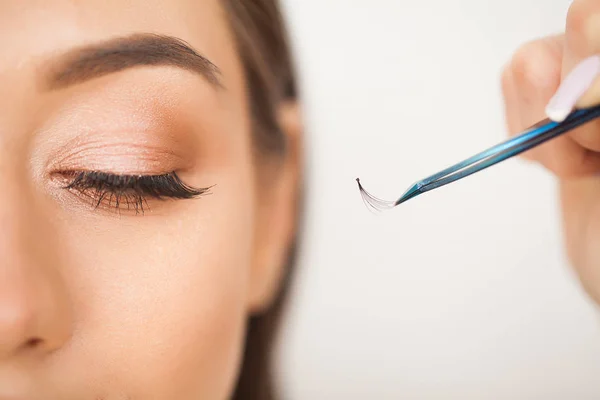 Eyelashes extensions. Fake Eyelashes. Eyelash Extension Procedure. Professional stylist lengthening female lashes. Master and a client in a beauty salon — Stock Photo, Image