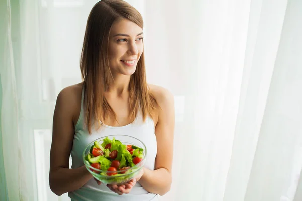 Kost. Ung kvinna äter sallad och håller en blandad sallad — Stockfoto