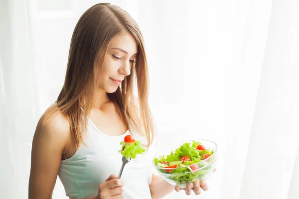Kost. Ung kvinna äter sallad och håller en blandad sallad — Stockfoto