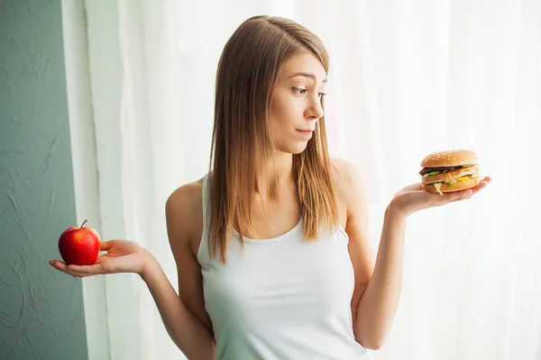 Концепция диеты, красивая молодая женщина выбирает между здоровой пищей и нездоровой пищей — стоковое фото