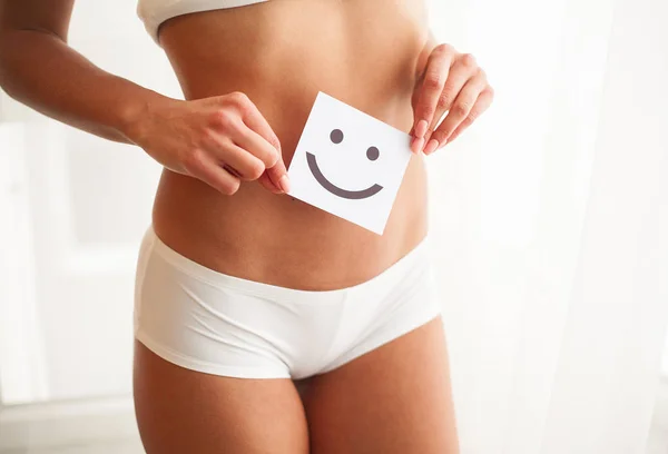 Salud de las mujeres. Primer plano de mujer sana con hermoso ajuste cuerpo delgado en bragas blancas sosteniendo la tarjeta blanca con la cara sonriente feliz en las manos. Salud estomacal y buenos conceptos de digestión — Foto de Stock