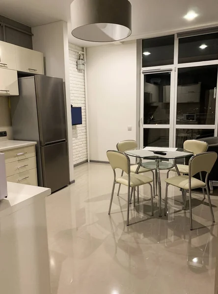 Interior de luz moderna da cozinha com mobiliário branco e mesa de jantar — Fotografia de Stock