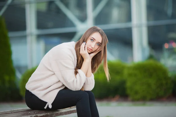 Mulher deprimida sentada em um parque da cidade em um banco — Fotografia de Stock
