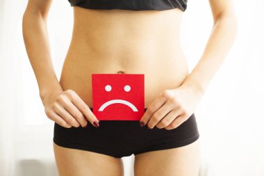 Kadın sağlığı. Kadın vücudu mide yakınındaki üzgün Smiley kartı tutan