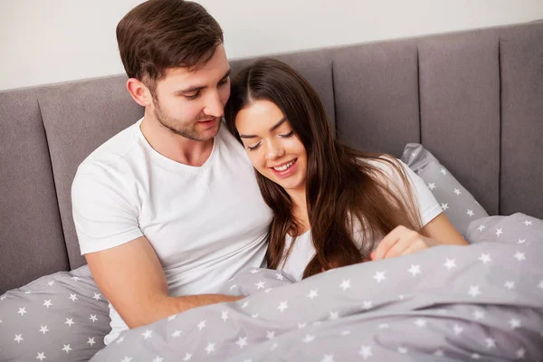 Pareja feliz divirtiéndose en la cama. Íntima sensual joven pareja en el dormitorio disfrutando el uno del otro — Foto de Stock
