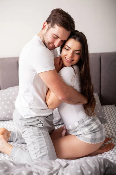 Pareja feliz divirtiéndose en la cama. Íntima sensual joven pareja en el dormitorio disfrutando el uno del otro —  Fotos de Stock