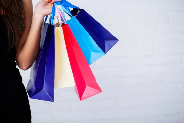 Compras. Primer plano de la mujer sosteniendo bolsa de compras de papel de color sobre fondo de pared blanco —  Fotos de Stock