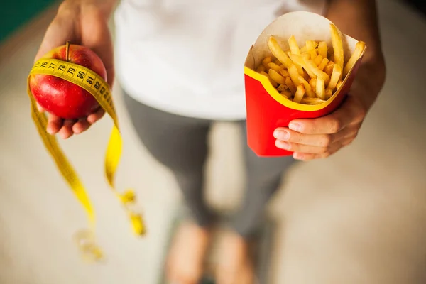 Diet and Healthy eating. Young Woman choosing between Fruits and junk food — Stock Photo, Image