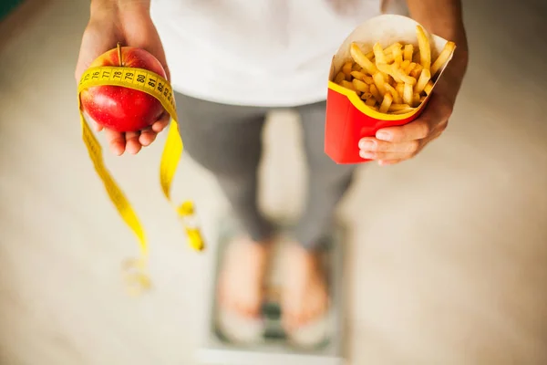 饮食和健康饮食。年轻妇女选择在果子和垃圾食物之间 — 图库照片