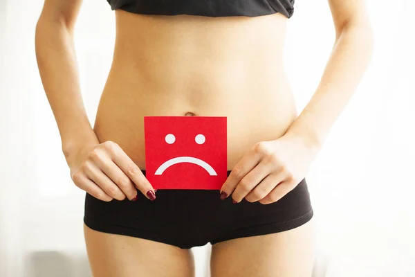 Salud de la mujer. Cuerpo femenino sosteniendo triste tarjeta sonriente cerca del estómago — Foto de Stock