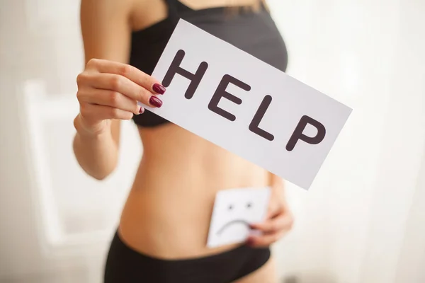 Saúde da mulher. Corpo feminino segurando símbolo cartão de ajuda perto do estômago — Fotografia de Stock
