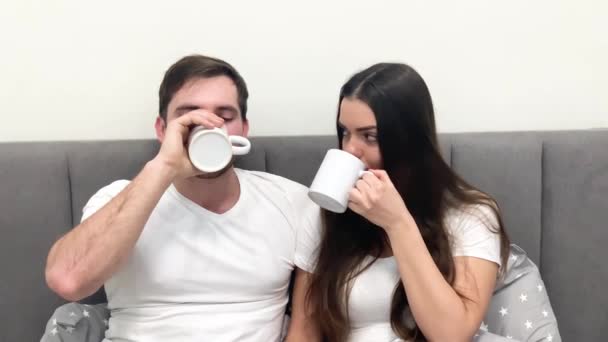 Güzel bir sabah. Genç çift yatakta kahve içiyor — Stok video