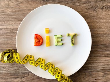 Tahta arka planda beyaz tabakta dilimlenmiş sebzelerden yapılan diyet.