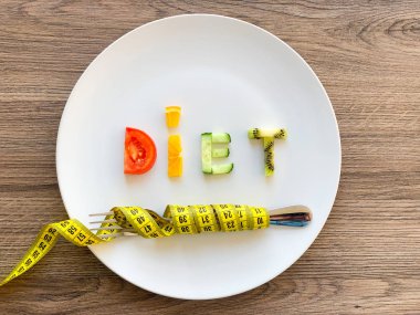 Kelime diyeti tabakta dilimlenmiş sebzelerden yapılır ve ahşap arka planda ölçülür.