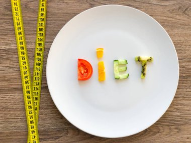 Kelime diyeti tabakta dilimlenmiş sebzelerden yapılır ve ahşap arka planda ölçülür.