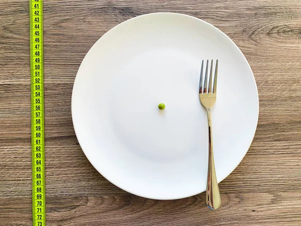 饮食。患有厌食症。在白色板上裁剪图像豌豆，带叉子和测量 — 图库照片