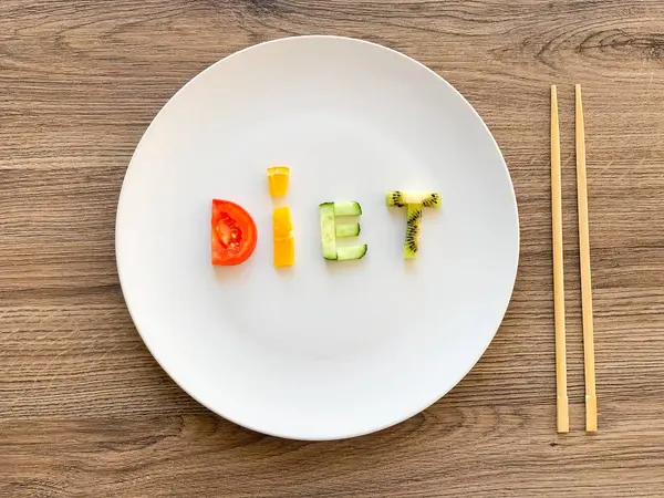 Word DIET made of sliced vegetables in white plate on wood background — Stock Photo, Image