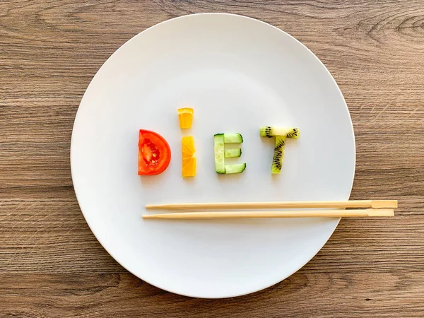 Word DIET made of sliced vegetables in white plate on wood background — Stock Photo, Image