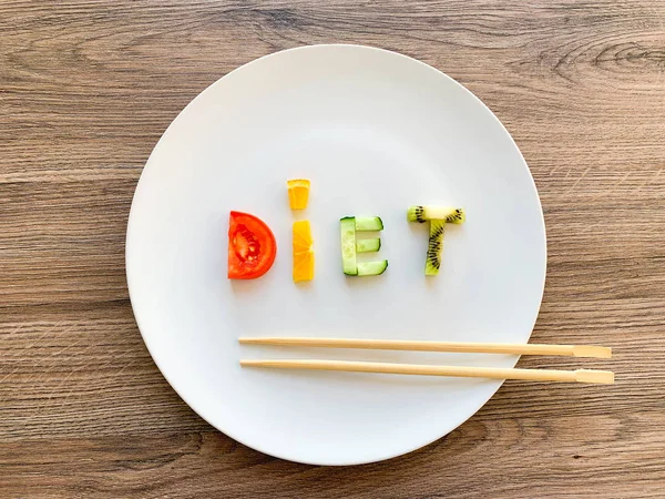 Word DIET made of sliced vegetables in white plate on wood background — Stock Photo, Image