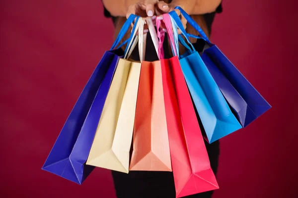 Shopping. Woman holding colored bags on red background in black friday holiday