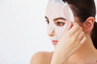 Spa ve gençleştirme konsepti. Çekici gülümseyen kadının yakın çekim ietkisi memnun, yüz kağıt maskesi kaldırır