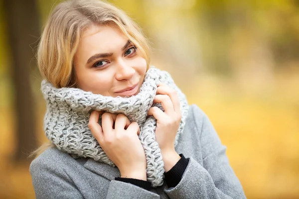 Cold and flu. Young woman in a gray coat walking in the autumn park and warms frozen hand — Stock Photo, Image