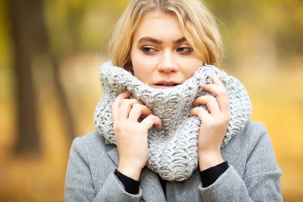 Холодно и грипп. Молодая женщина в сером пальто гуляет по осеннему парку и согревает замерзшую руку — стоковое фото