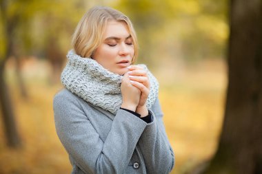 Soğuk algınlığı ve grip. Sonbahar park ve el donmuş sıcak yürüyüş gri paltolu genç kadın