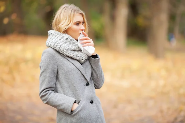 Mädchen niesen in Gewebe. junge Frau bläst ihre Nase in den Park. Frauenporträt Niesen im Freien wegen Erkältung und Grippe — Stockfoto