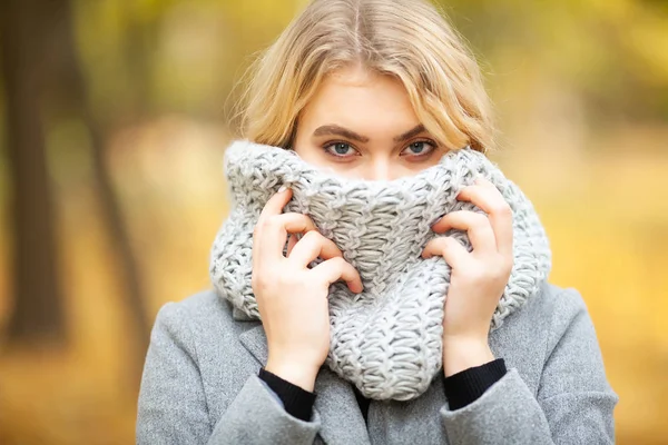 Resfriado y gripe. Mujer joven en un abrigo gris caminando en el parque de otoño y calienta la mano congelada — Foto de Stock