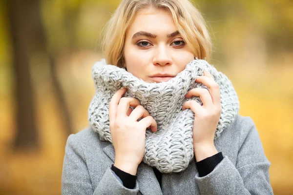 Cold and flu. Young woman in a gray coat walking in the autumn park and warms frozen hand — Stock Photo, Image