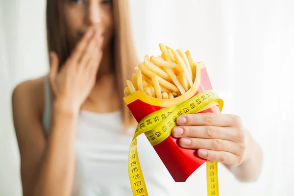 Диета. Женщина, стоящая на весах и держащая чипсы. Понятие здорового питания. Здоровый образ жизни. Диета — стоковое фото