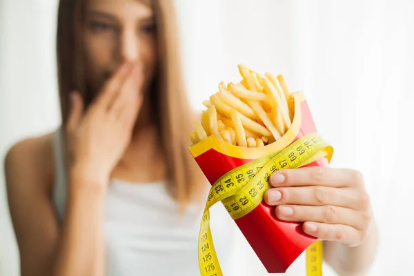 Dieta. Mujer parada en escamas y sosteniendo papas fritas. El concepto de alimentación saludable. Un estilo de vida saludable. Dieta — Foto de Stock