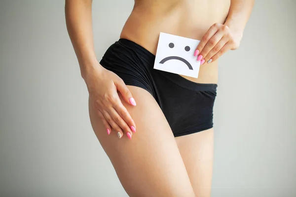 Salud de la mujer. Cuerpo femenino sosteniendo triste tarjeta sonriente cerca del estómago — Foto de Stock