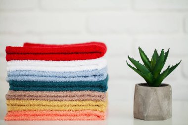 Dekor ve beyaz arka plan ile hafif ahşap masa üzerinde kabarık banyo havluları