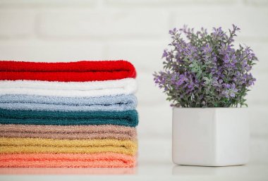 Dekor ve beyaz arka plan ile hafif ahşap masa üzerinde kabarık banyo havluları