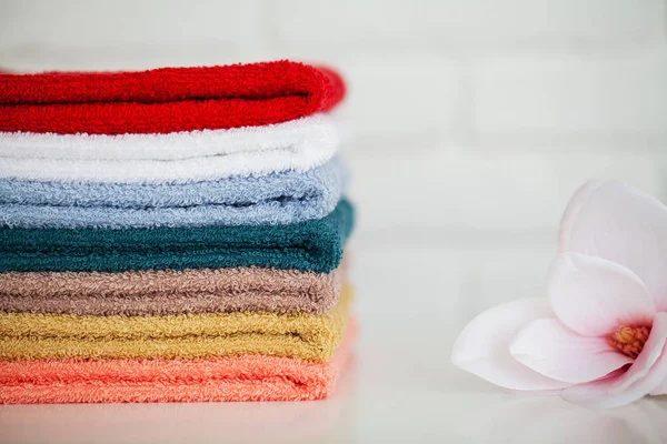 Toallas de baño esponjosas sobre mesa de madera clara con decoración y fondo blanco — Foto de Stock