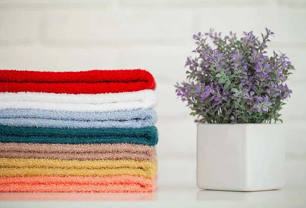 Toallas de baño esponjosas sobre mesa de madera clara con decoración y fondo blanco — Foto de Stock