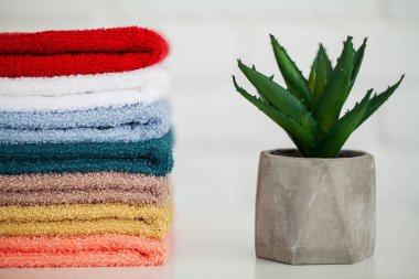 Dekor ve beyaz arka plan ile hafif ahşap masa üzerinde kabarık banyo havluları