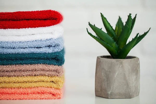 Dekor ve beyaz arka plan ile hafif ahşap masa üzerinde kabarık banyo havluları