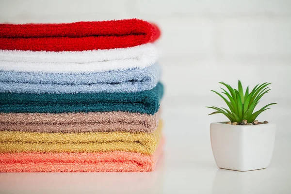 Toallas de baño esponjosas sobre mesa de madera clara con decoración y fondo blanco — Foto de Stock