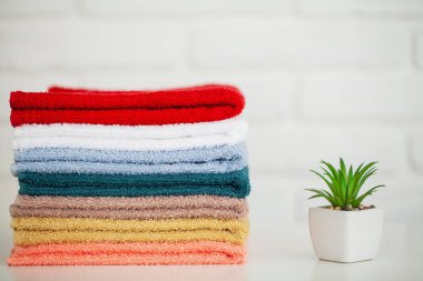 Dekor ve beyaz arka plan ile hafif ahşap masa üzerinde kabarık banyo havluları