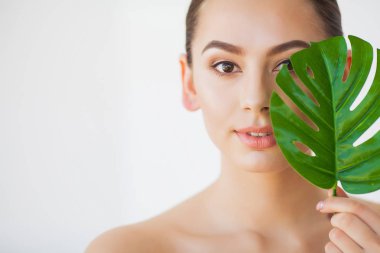 Spa bakımı. Büyük yeşil yapraklı genç güzel esmer kadın