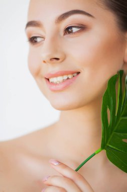 Spa bakımı. Büyük yeşil yapraklı genç güzel esmer kadın