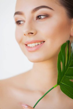 Spa bakımı. Büyük yeşil yapraklı genç güzel esmer kadın